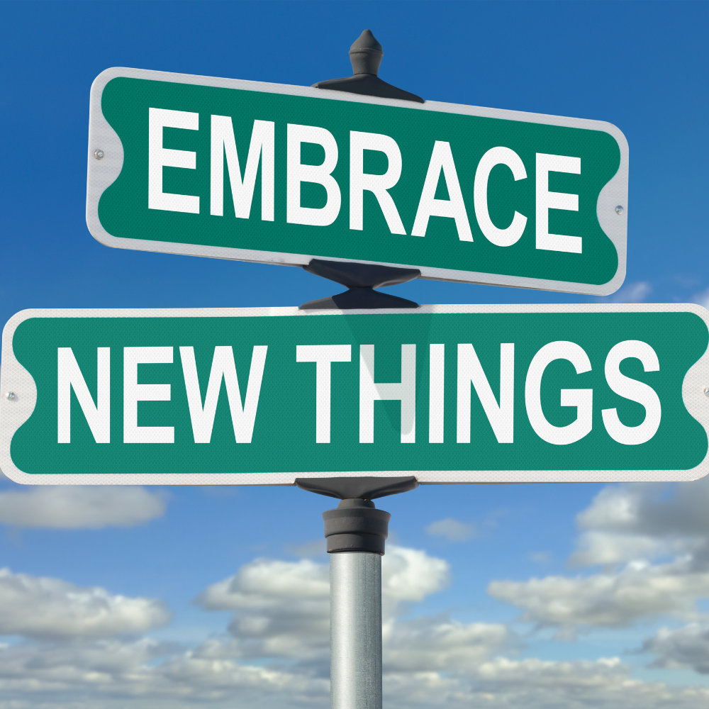 A crossroads sign that says "Embrace New Things"